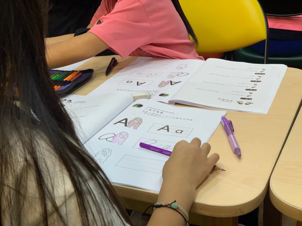 孩子在課堂上用紫色筆描寫英文字母練習本